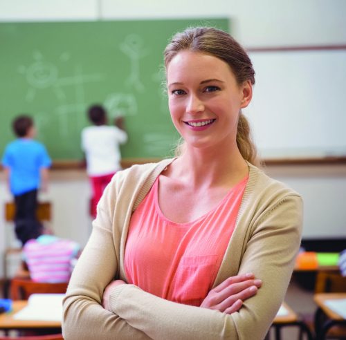 Pretty teacher smiling at camera at back of classroom