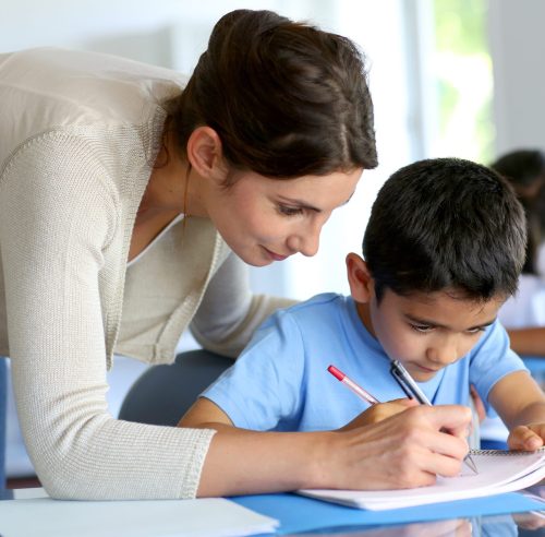 Teacher helping young boy with writing lesson