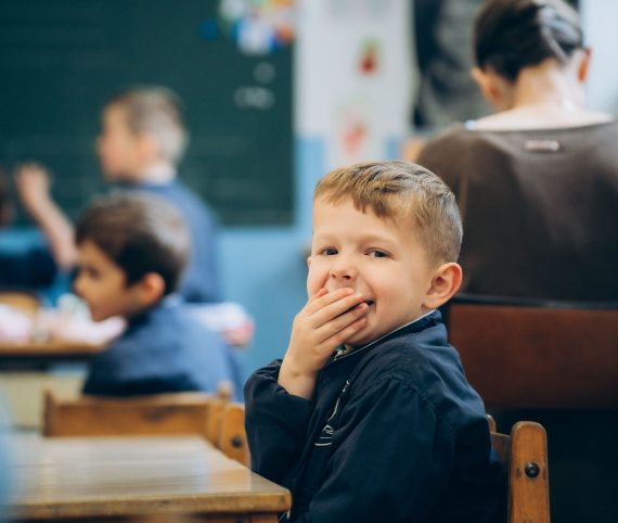 petit garçon rigole salle classe